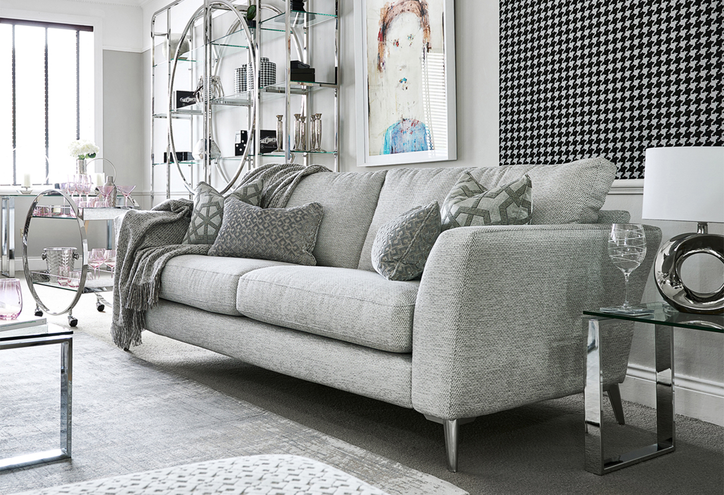 Chilton 3 seater sofa in a grey colour, with cushions and a throw in matching colours.
