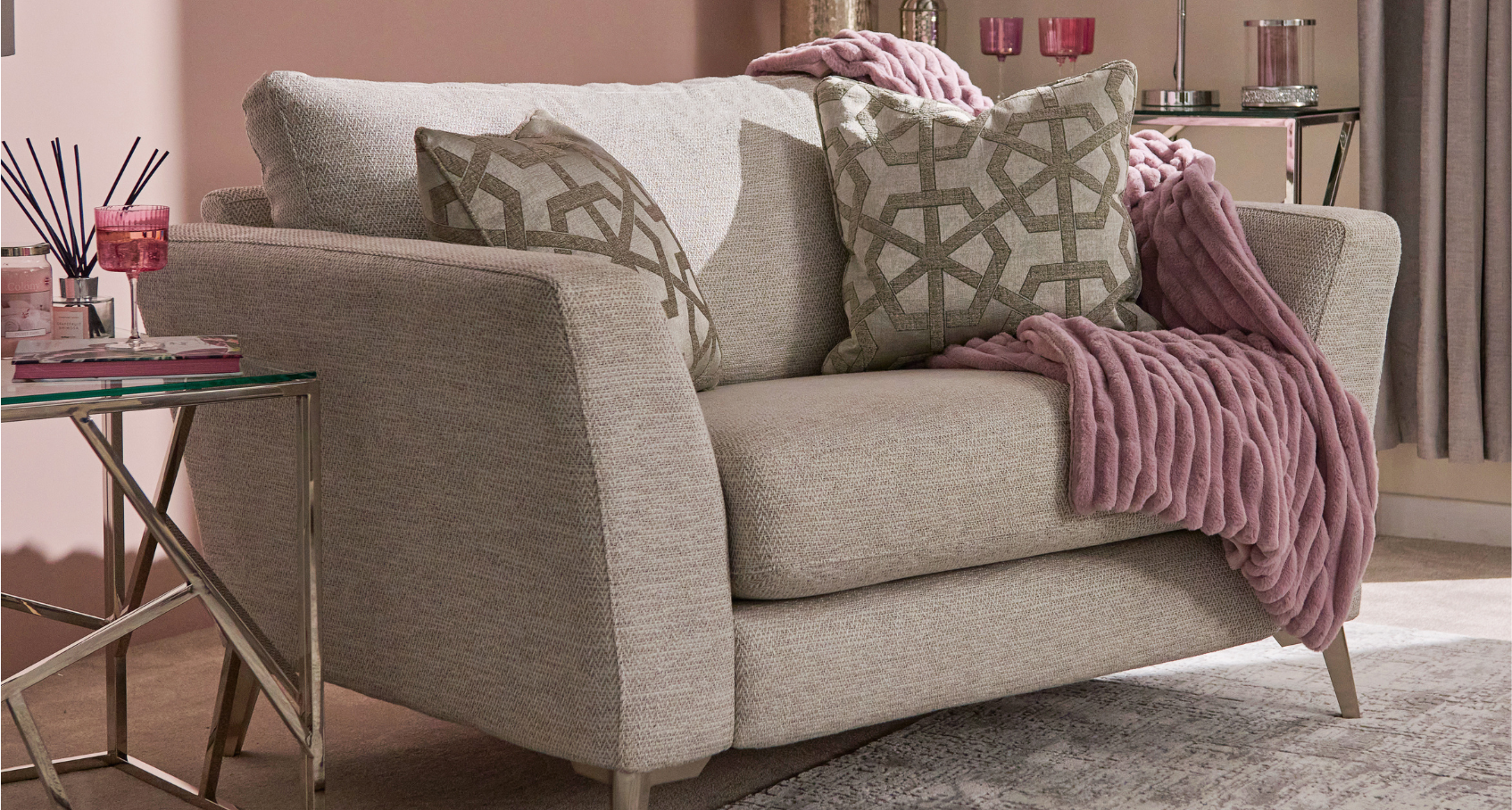 An image of the Chilton loveseat with matching cushions and a pink throw, in a living space styled with pink-toned accessories.