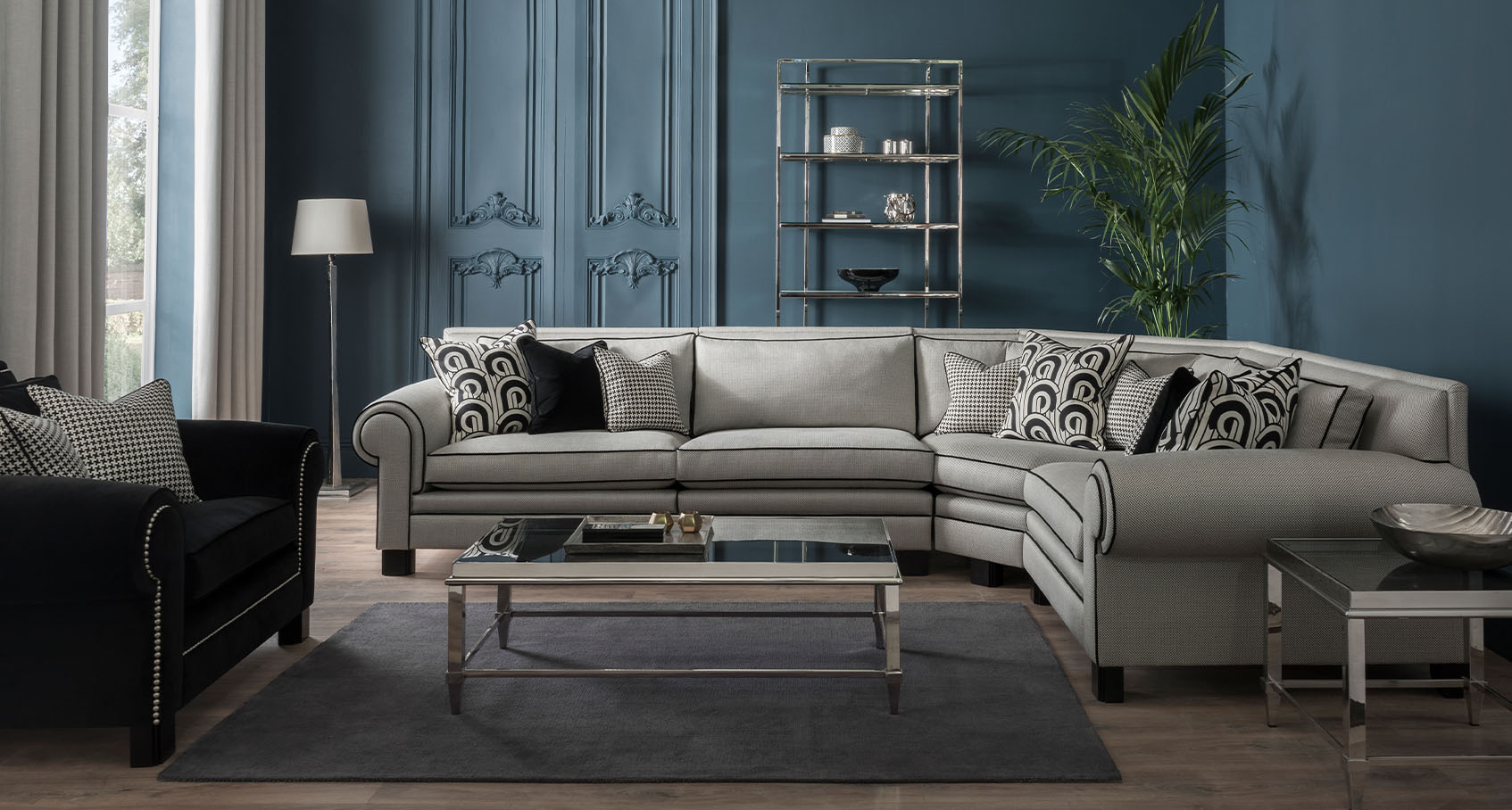 coco large corner sofa in cream fabric with black ribbing all around styled with houndstooth, black and abstract cushions in a blue decorated room