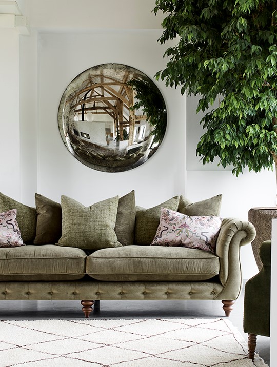 A stylish Alexander & James chesterfield sofa made of fabric in pale green colour displayed in a living room and accessorised with lots of scatter cushions