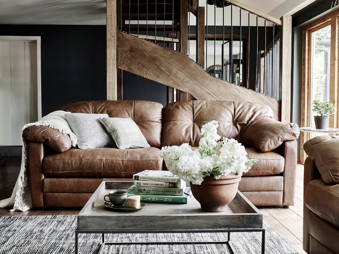 Gorgeous Alexander and James Bailey leather sofa in brown leather displayed in a living room and accessorised with beige cushions and a cosy throw