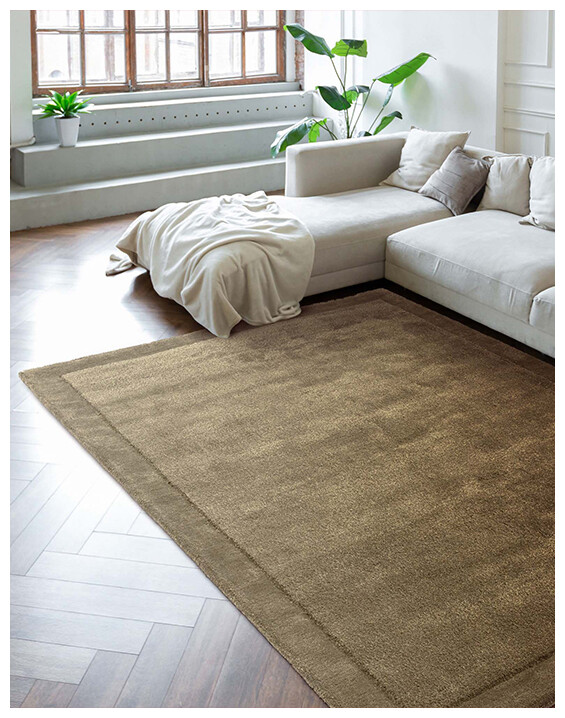 The Harris Olive Rug in a modern living room with a cream sofa and natural lighting.