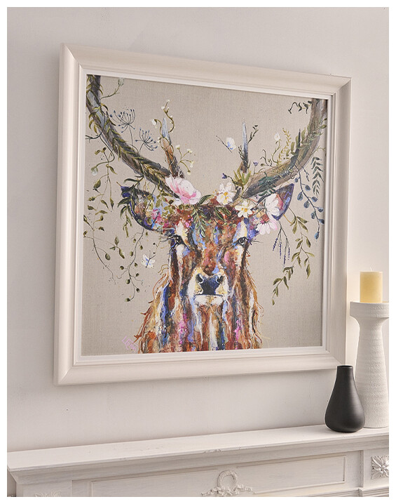 A Colourful Stag Framed Print hanging on a white wall above a white, detailed mantelpiece.