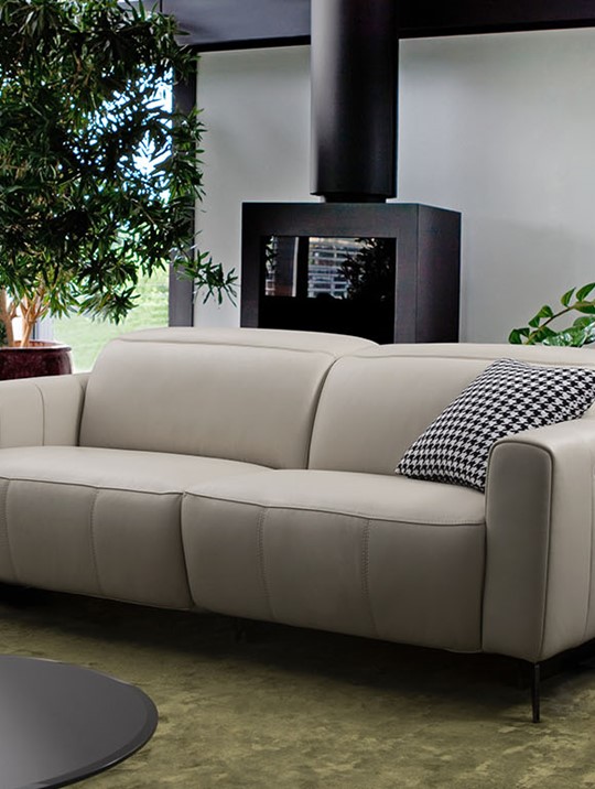 cream leather fabbrica 2 seater sofa in a light livingroom with greenery all around