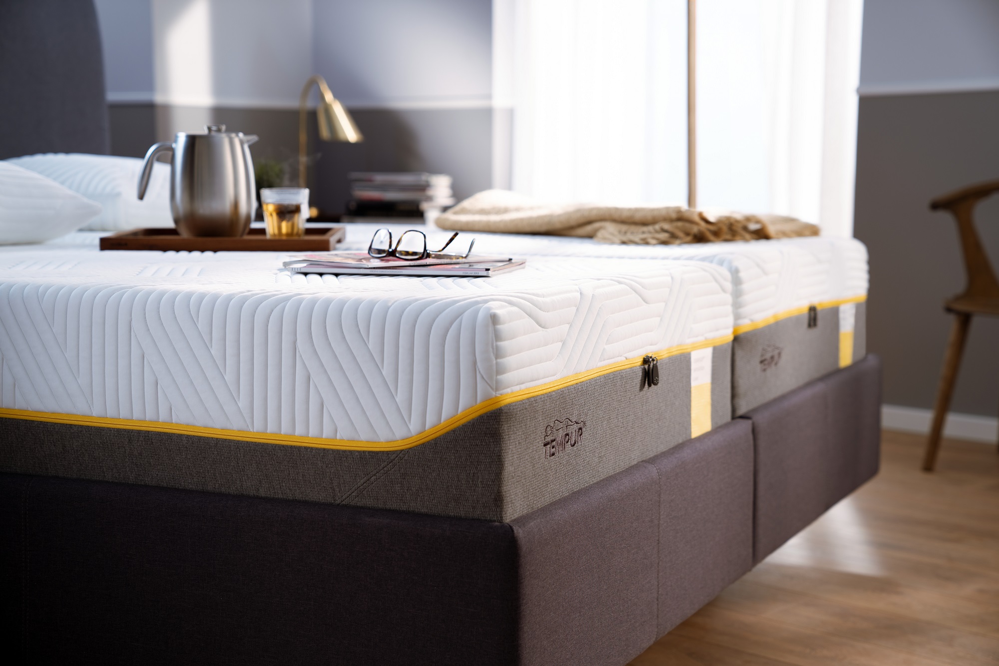 An image of the Tempur Sensation Lux Mattress on a bed with personal belongings on top.